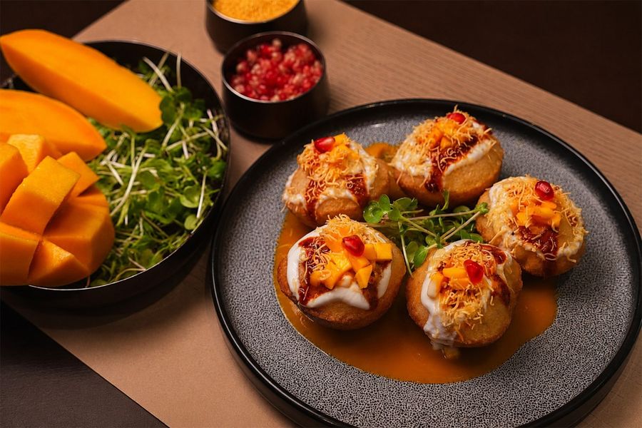 Filled puris topped with chutney, served with sliced mango