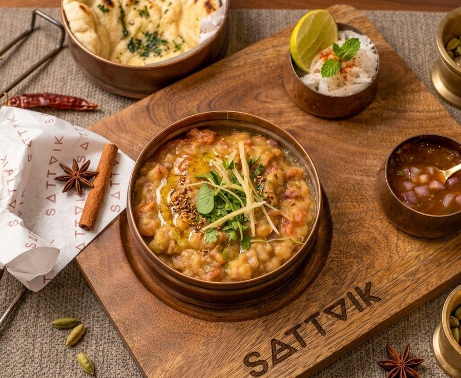A bowl of chole served on a wooden board with bread