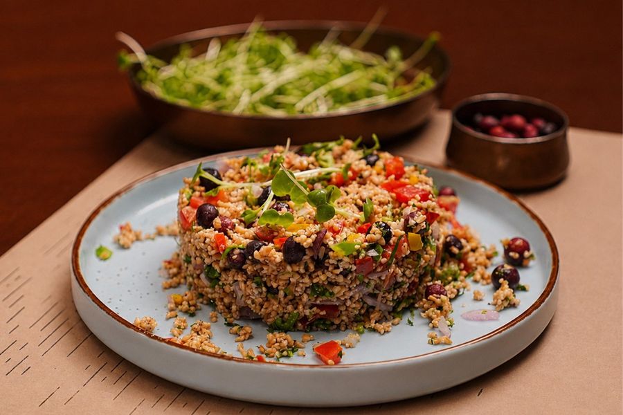 A salad plated with grains, greens and pomegranate