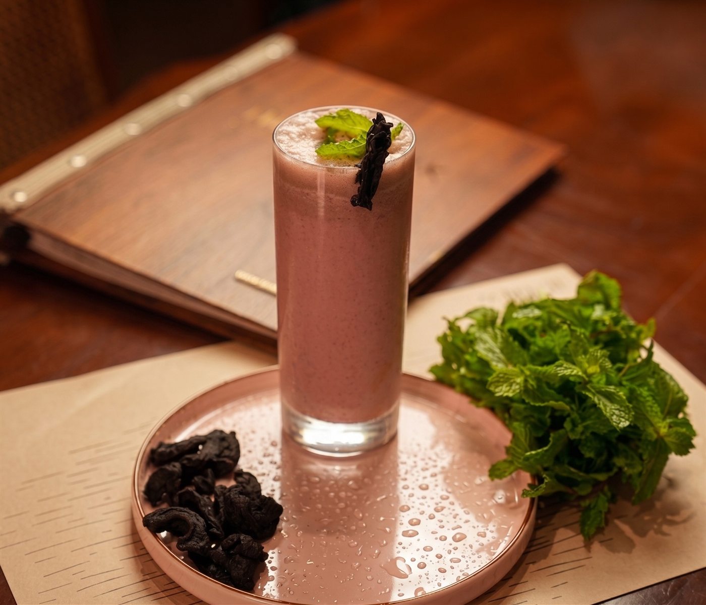 A chilled pink cooler garnished with mint, with dried fruit on the side
