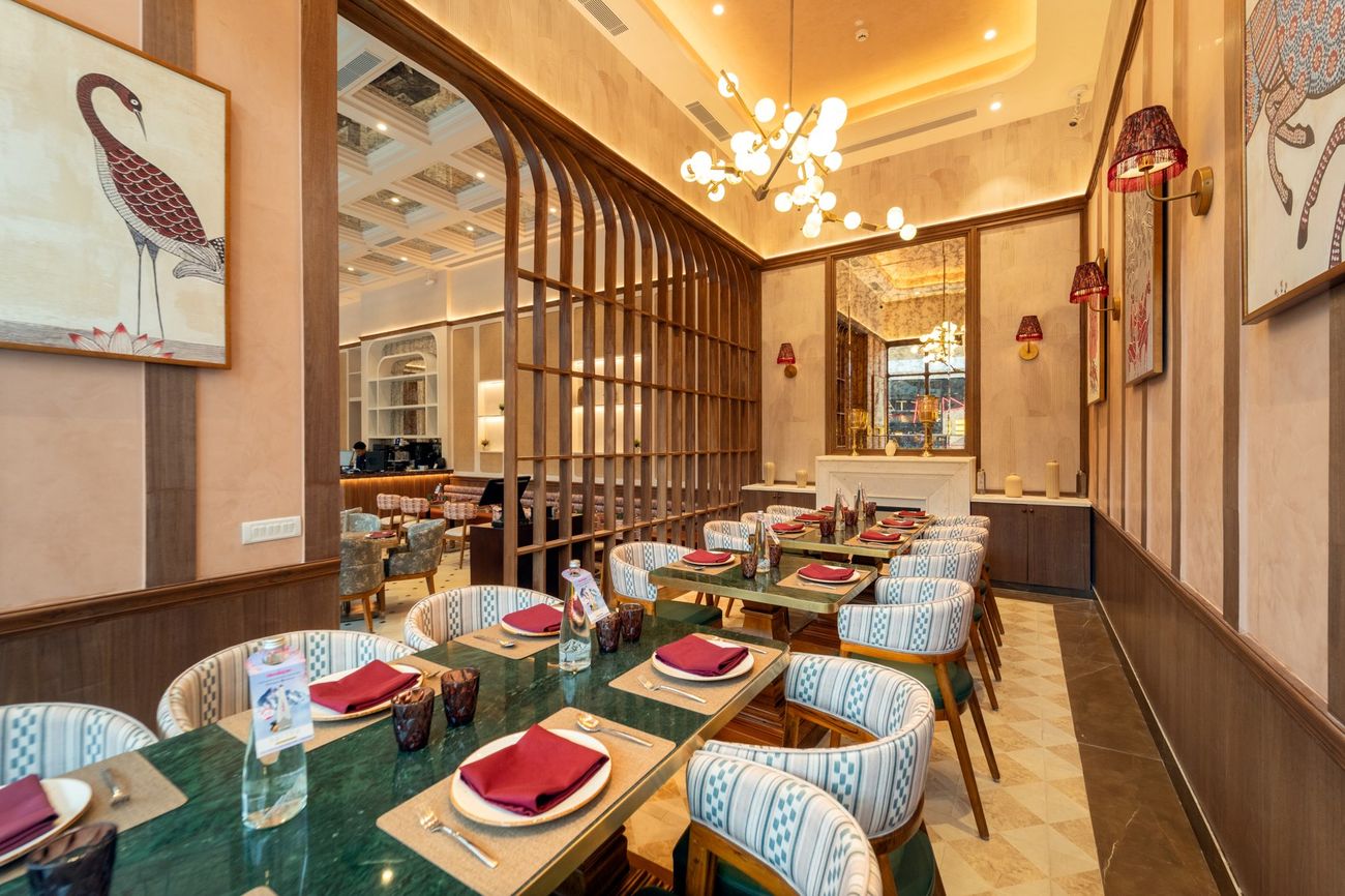 The dining room at Sattvik, with pendant lamps, patterned chairs and framed art